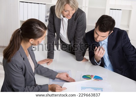 Business team of man and woman sitting around a table talking together in a meeting.