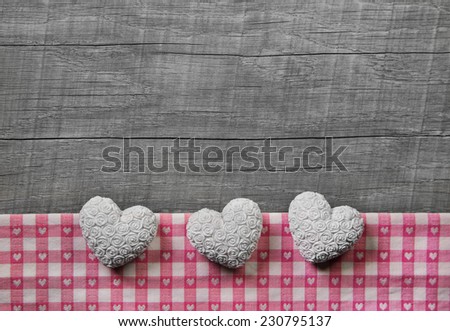 Greeting card: three white and pink checked hearts on wooden grey shabby chic background.