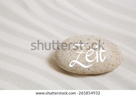 Stone in the sand with german text: time. Idea background for concepts.