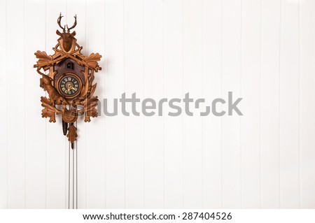 Wooden old cuckoo clock hanging on a white wall.