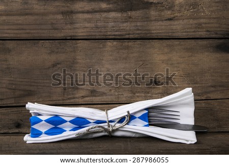 Bavarian food. Old wooden background with knife and fork. Table decoration with blue and white checked napkin and cutlery.