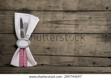 Silver cutlery in red and white checked with napkin on an old wooden background.