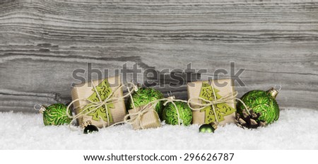 Christmas presents and green balls on wooden old grey background with snow for decorations.