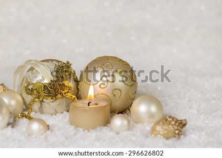 Festive classical christmas decoration in white and gold with horse and one burning candle for the first advent.
