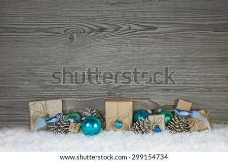 Grey wooden christmas background with turquoise decoration and gifts wrapped in paper.