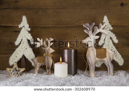Christmas decoration with natural material. Two burning candles with elk and snow on wooden old rustic background.