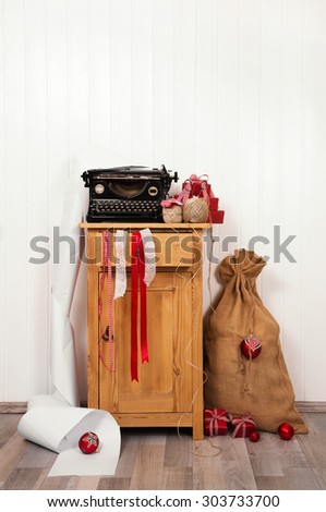 Writing christmas wishes with an antique typewriter. Vintage Xmas red and white decoration on old wooden background.
