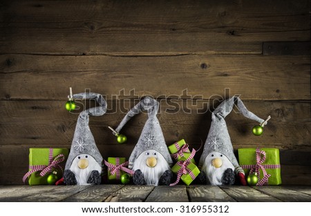 Three santa with red felt hats and apple green christmas presents on an old wooden background for decoration.