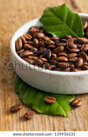 coffee beans and coffee leaves in a bowl