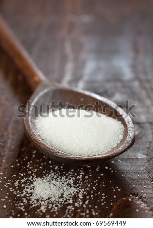 pure loose white sugar on wooden spoon