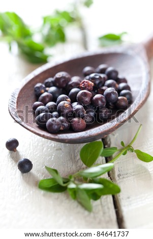 dried juniper berries on wooden spoon
