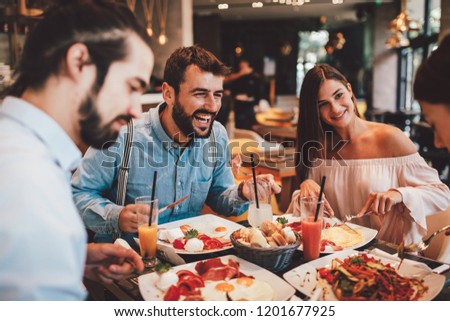 Group of Happy friends having breakfast in the restaurant