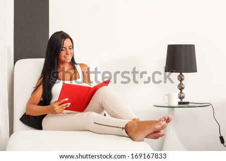 Beautiful woman sitting on the sofa and  reading a book. Selective focus on face.