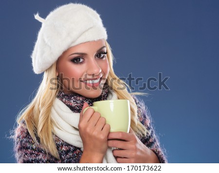 Beautiful young woman with beret and scarf around the neck holding teacup