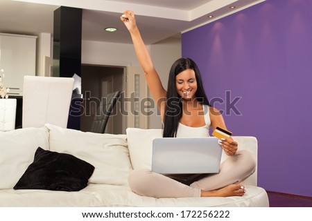 Young woman sitting on the sofa and  shopping online with credit card