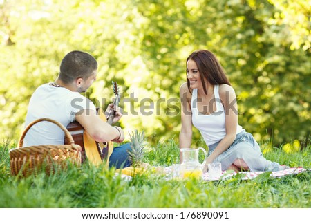 Young man playing the guitar and flirting with a woman. Selective focus on woman.
