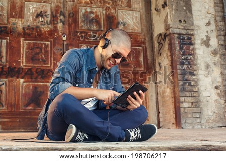 handsome young man listening to music with headphones via tablet PC