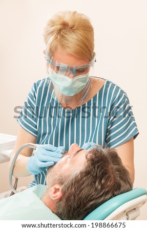 Dentist drilling tooth of adult man