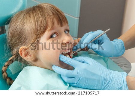 Close-up of little girl having her teeth checked by dentist