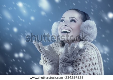 Woman in winter clothes catching snowflakes in the studio