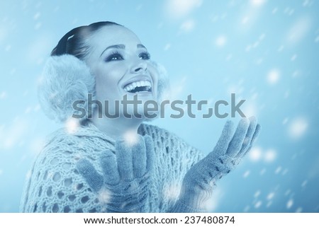 Woman in winter clothes catching snowflakes