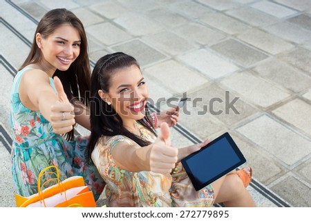 Two young women buying online through a digital tablet. Selective focus on right woman.