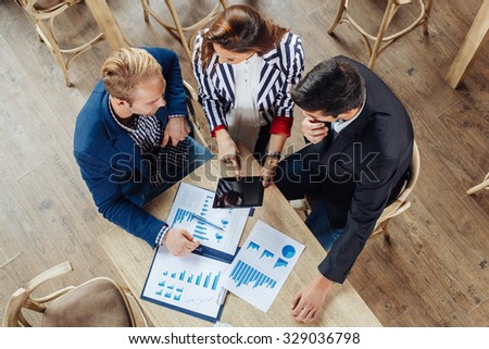 Small group of business people at a meeting in a cafe. Selective focus on papers and table.