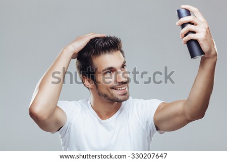 Young man applying hair spray to his hair