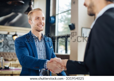 Two businessman shaking hands in a cafe