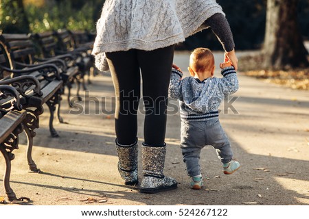Mom teaching her son\'s first baby steps in the park