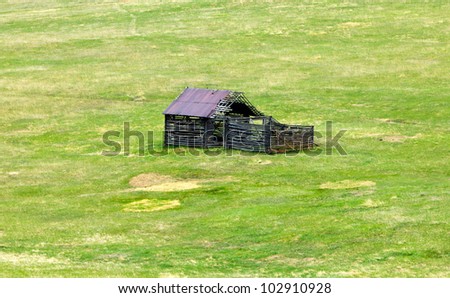 Old abandoned log cabin in a green grass field