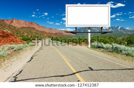 Blank billboard sign by empty highway through desert landscape