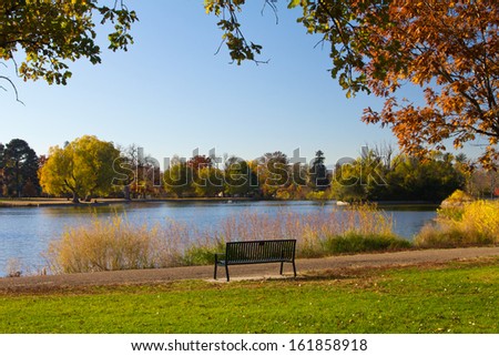 Empty park bench by lake in the fall - Denver, Colorado