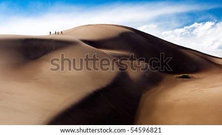 A group of four people climb to the top of the dune field of the Great Sand Dunes National Park in Colorado