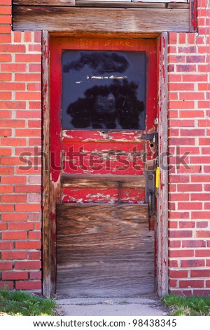 Old wooden door with peeling red paint in a brick wall