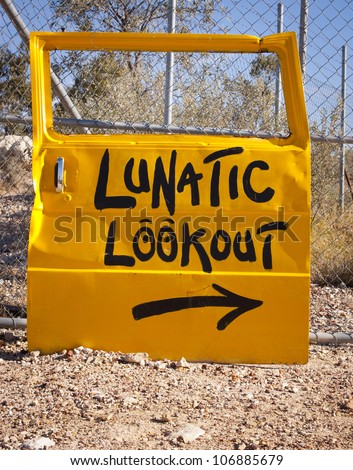 Classic Australian outback bush humor, with a car door pointing to Lunatic Lookout