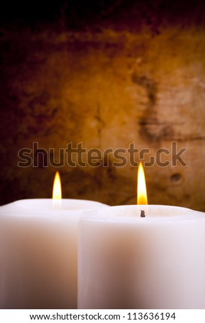 White candles burning with a textured vintage background
