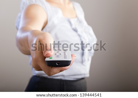 Business woman holds a remote control in her hands with her body out of focus
