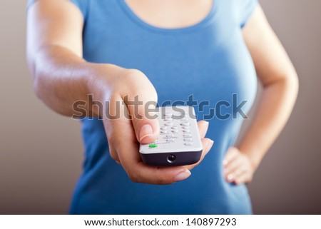 Woman holds a remote control in her hands with her body out of focus