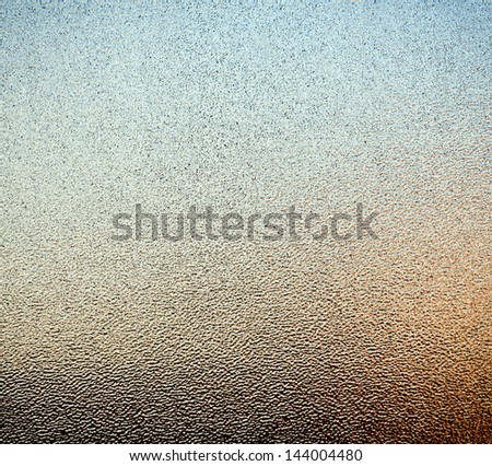 Abstract of stippled glass window pane with ambient colours from outside as background texture