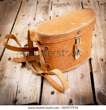Old vintage leather bag with leather strap on wooden table