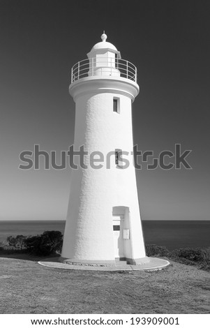 Grand white washed lighthouse looks over the deep blue ocean