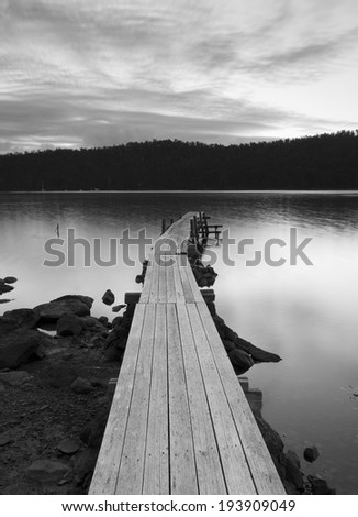 Sunset over water and jetty in black and white