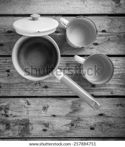 Old cups and saucepan in a retro kitchen table setting in black and white