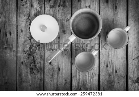 Old cups and saucepan in a retro kitchen table setting in black and white