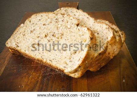 Wide slices of bread with mixed grains on a timber bread board