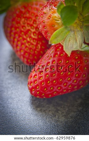 Bright, vibrant red strawberries close up on dark bench top