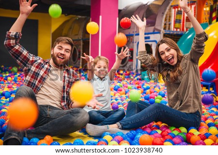 Image of emotional cheerful little child have fun with his parents in entertainment game center.