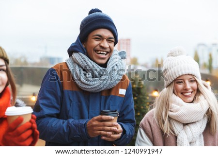 Photo of a happy young friends talking with each other drinking coffee outdoors winter concept.