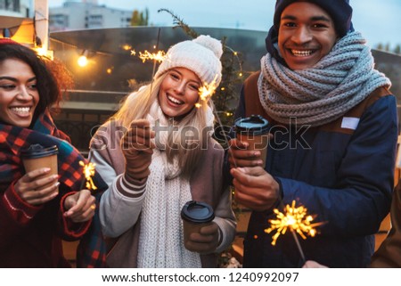 Image of a happy young friends talking with each other drinking coffee outdoors winter concept.